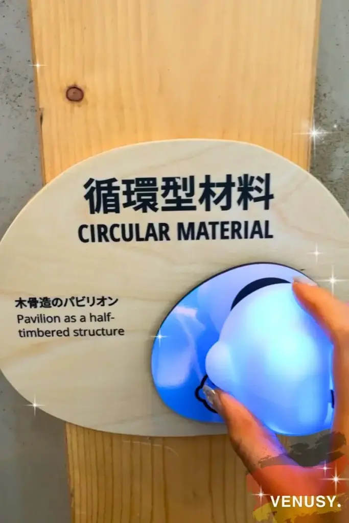 大阪・関西万博2025 ドイツ館で展示された「循環型材料」のサインに、公式キャラクター「サーキュラーちゃん」の音声ガイドをかざす様子。