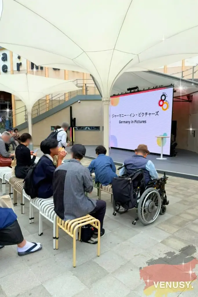 大阪・関西万博ドイツ館の屋外ステージで、「Germany in Pictures」という映像イベントを見ている来場者の様子。