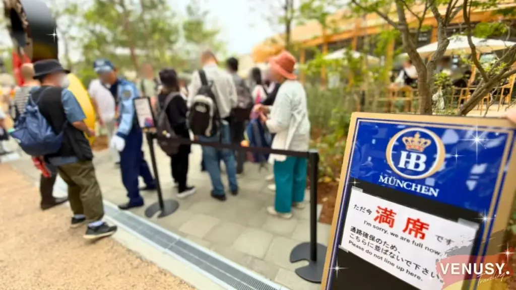 大阪・関西万博2025 ドイツ館レストラン「Oishii! Germany」に並ぶ人々と「満席」案内看板。人気の高さが伝わる混雑風景。