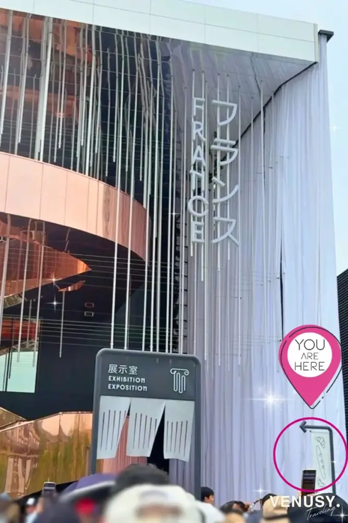 大阪万博フランス館限定クロワッサンが買えるパン屋の入口位置を示す「YOU ARE HERE」マーク付き外観写真