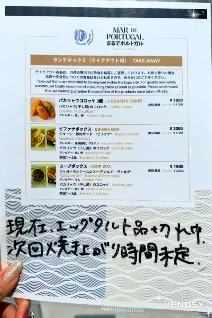大阪・関西万博ポルトガル館のフードメニュー表。エッグタルトは品切れで「次回入荷時間未定」と手書きで案内されている様子。