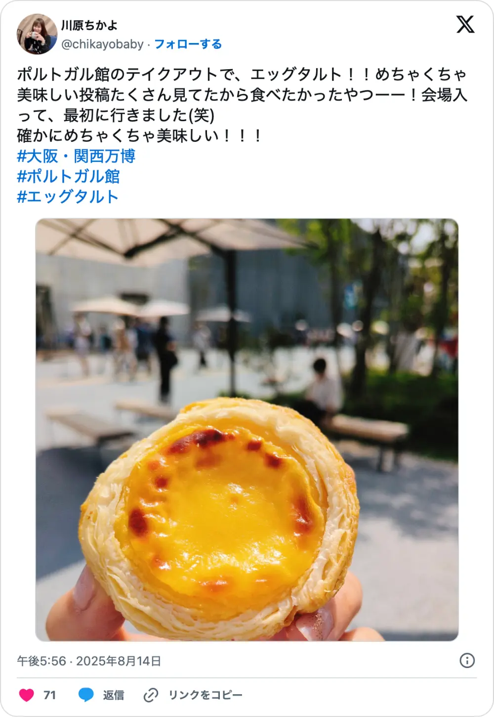 大阪万博ポルトガル館エッグタルトを紹介するX（旧Twitter）の投稿。手に持った焼き色の美しいエッグタルトがアップで写っている。
