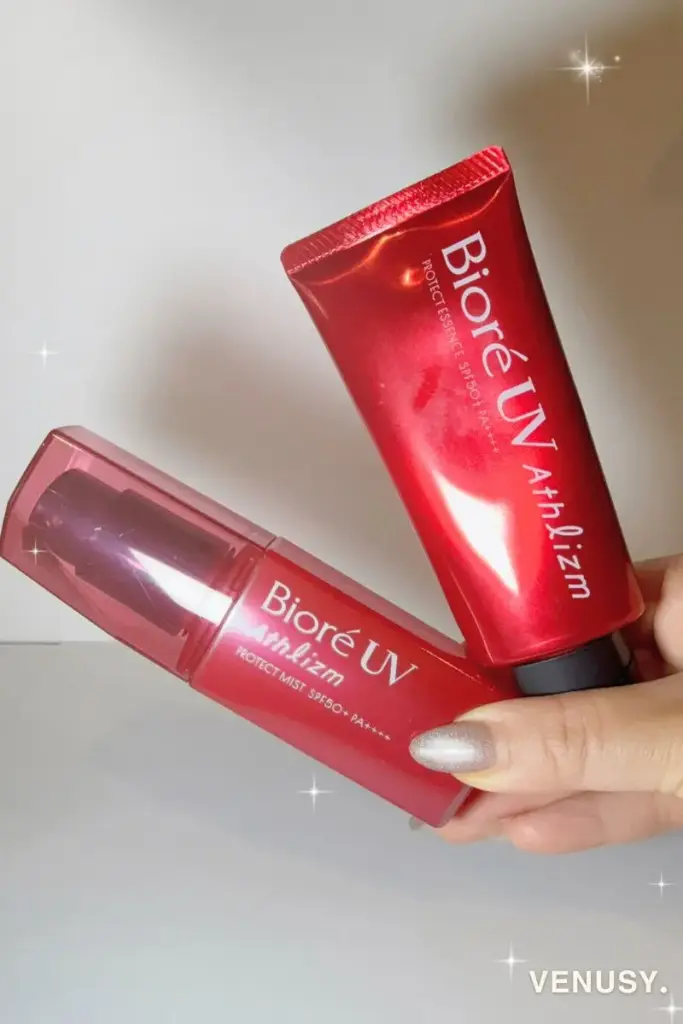 夏の大阪万博おすすめ持ち物アスリズム。Biore UV Athlizmシリーズの日焼け止め2種（エッセンスとミスト）を手に持っている写真。真夏の強い紫外線対策に最適な赤いパッケージ。