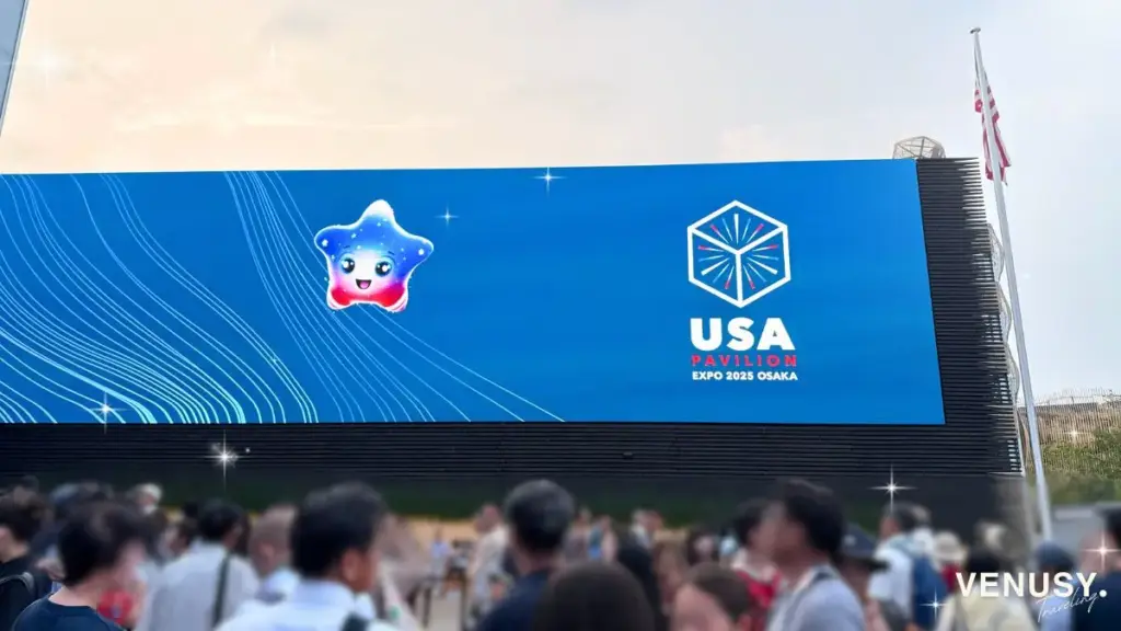 大阪万博アメリカ館のキャラクターSparkちゃんと待機する来場者たち