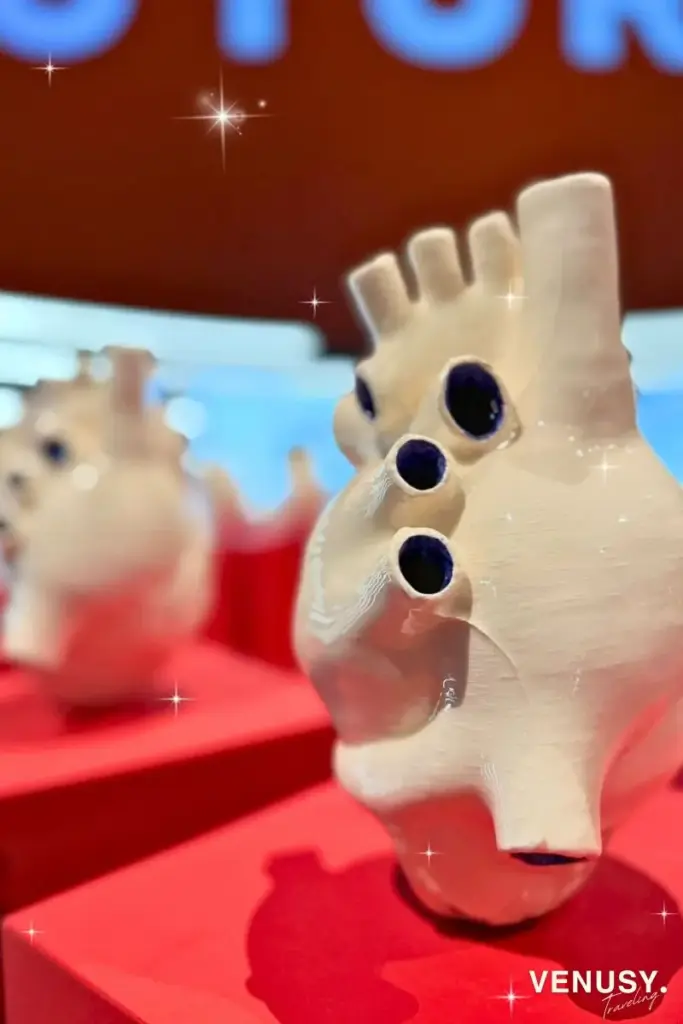 大阪万博イタリア館作品《循環器系》。陶器でできた白い心臓が赤い台の上に円形に並ぶ現代アート展示